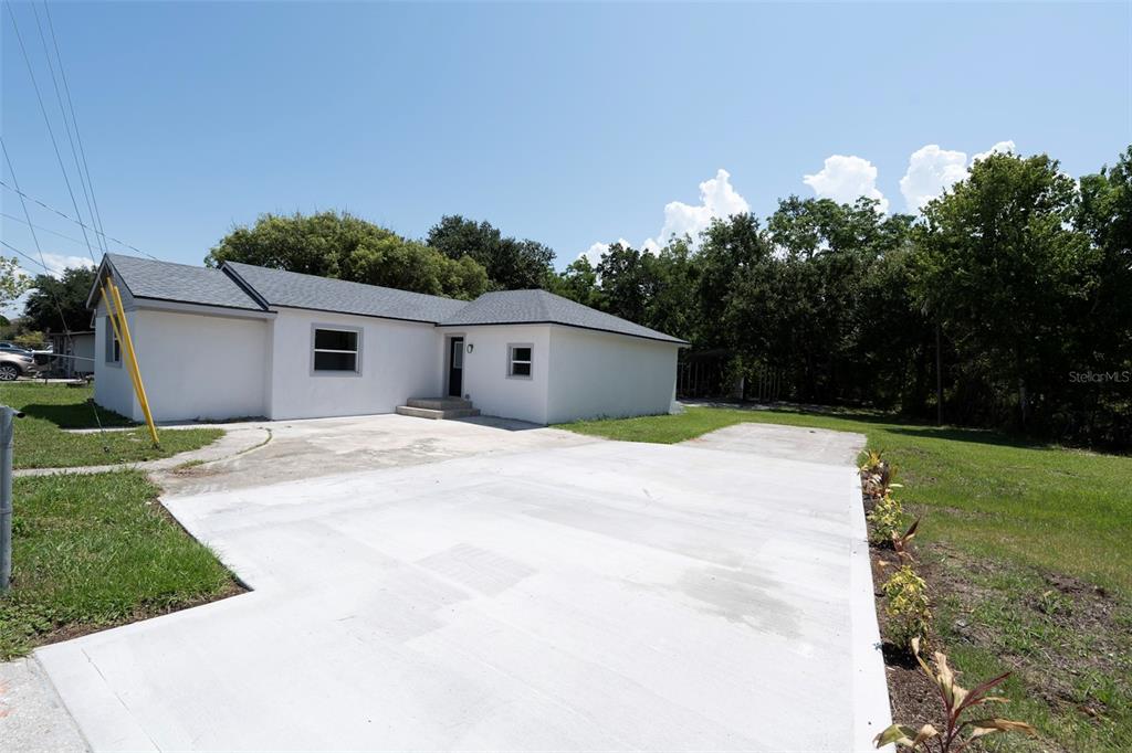 A white single-story house with a gray roof and a large concrete driveway — 689 BETHUNE AVENUE, WINTER GARDEN, FL