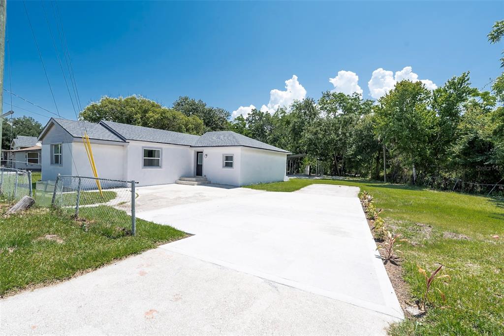 A white single-story house features a large concrete driveway and a chain-link fence — 689 BETHUNE AVENUE, WINTER GARDEN, FL