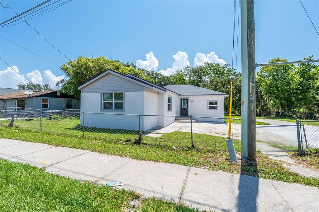 A single-story house with a white exterior and gray roof sits behind a chain-link fence — 689 BETHUNE AVENUE, WINTER GARDEN, FL