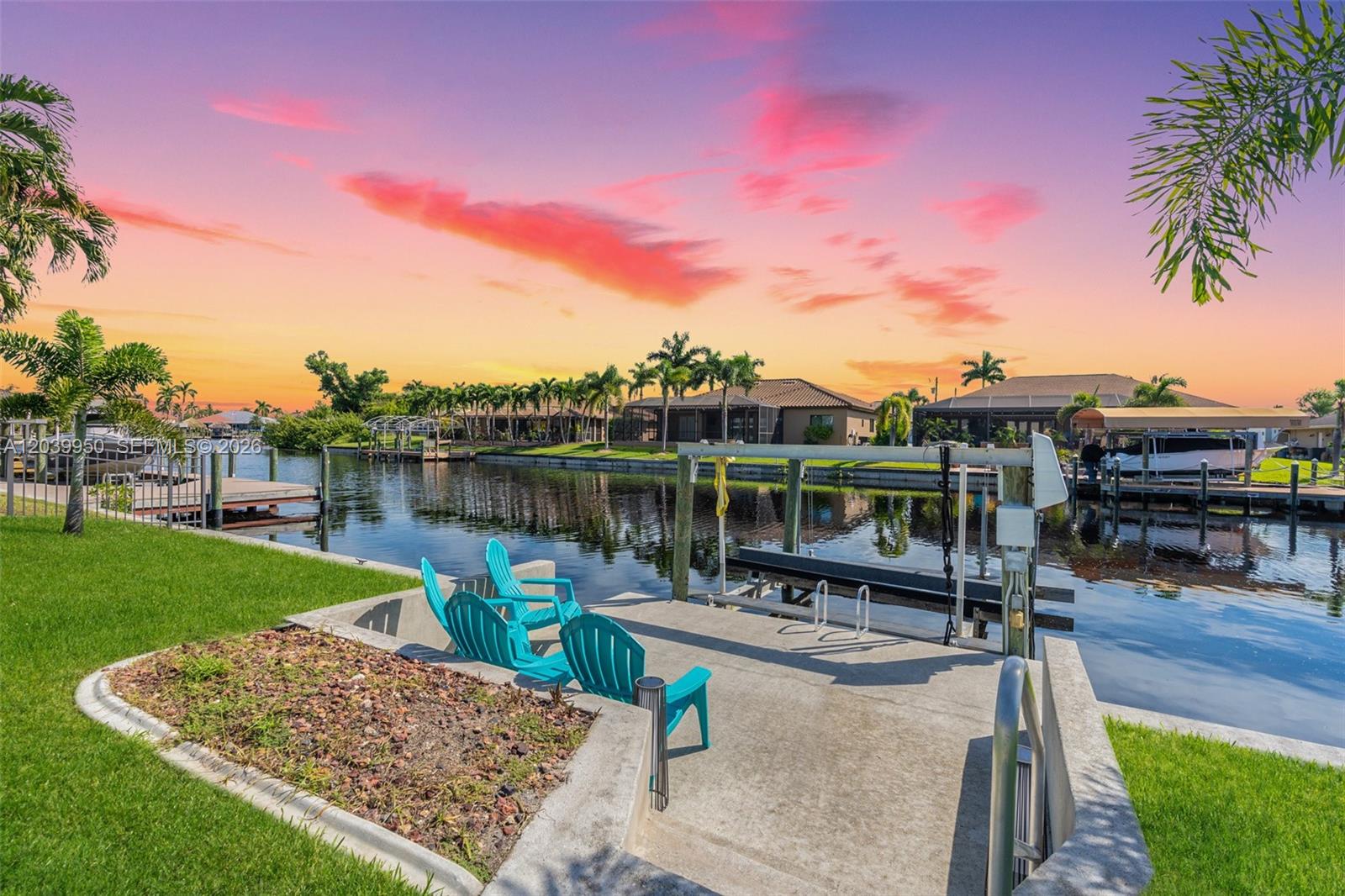 A concrete boat dock with turquoise chairs overlooks a canal at sunset — 2219 SE 19 PL, Cape Coral FL 33990, CAPE CORAL, FL