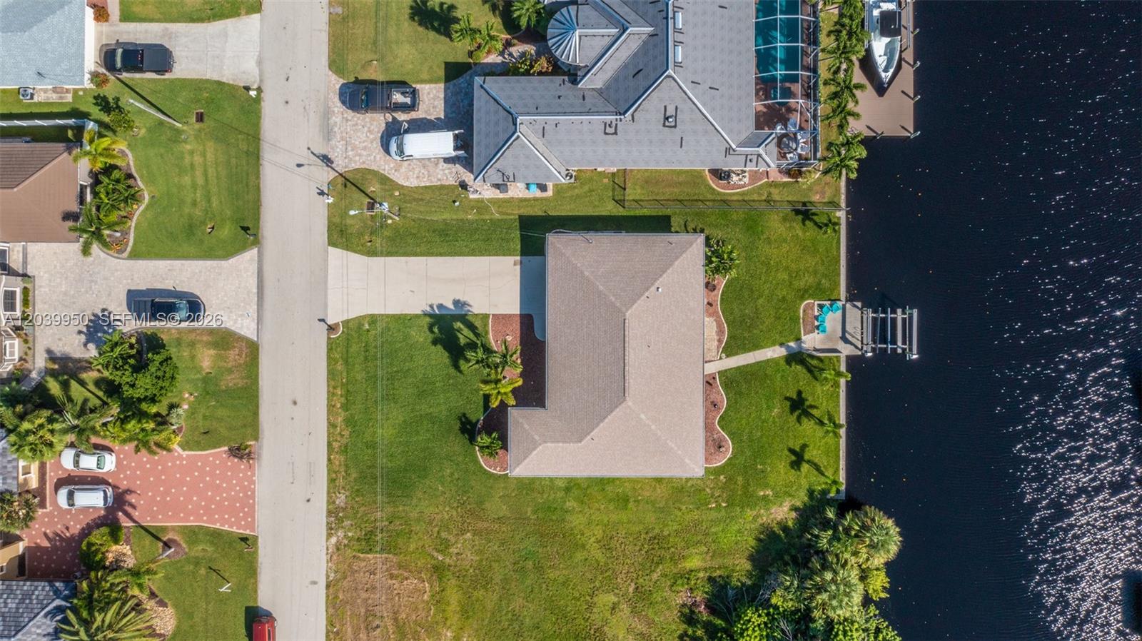 An aerial view shows a house with a driveway and dock along a canal — 2219 SE 19 PL, Cape Coral FL 33990, CAPE CORAL, FL