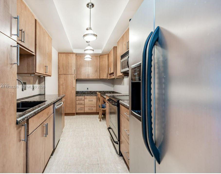 A galley kitchen features light wood cabinets, granite countertops, and stainless steel appliances — 4001 Hillcrest Dr # 914, Hollywood FL 33021, HOLLYWOOD, FL