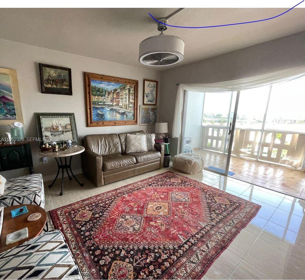 A living room features a brown leather sofa, a large red rug, and balcony access — 4001 Hillcrest Dr # 914, Hollywood FL 33021, HOLLYWOOD, FL