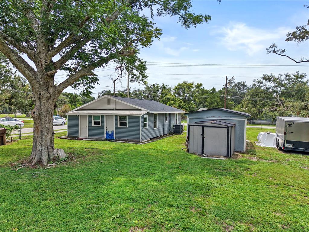 A gray house with a shed and a large tree in a grassy backyard — 204 PINE AVENUE, POLK CITY, FL