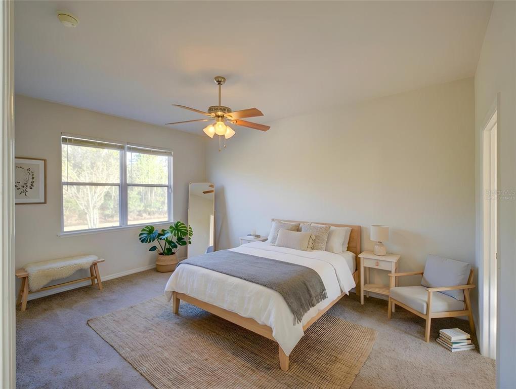 A bedroom features a bed, a ceiling fan, a window, and a chair on carpet — 735 PALAISEAU CT, KISSIMMEE, FL