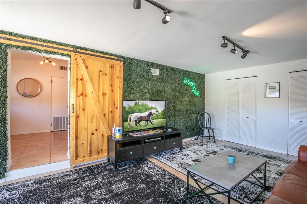 A living room features a green wall, a wooden barn door, and a black media console — 901 HARMON AVENUE, WINTER PARK, FL