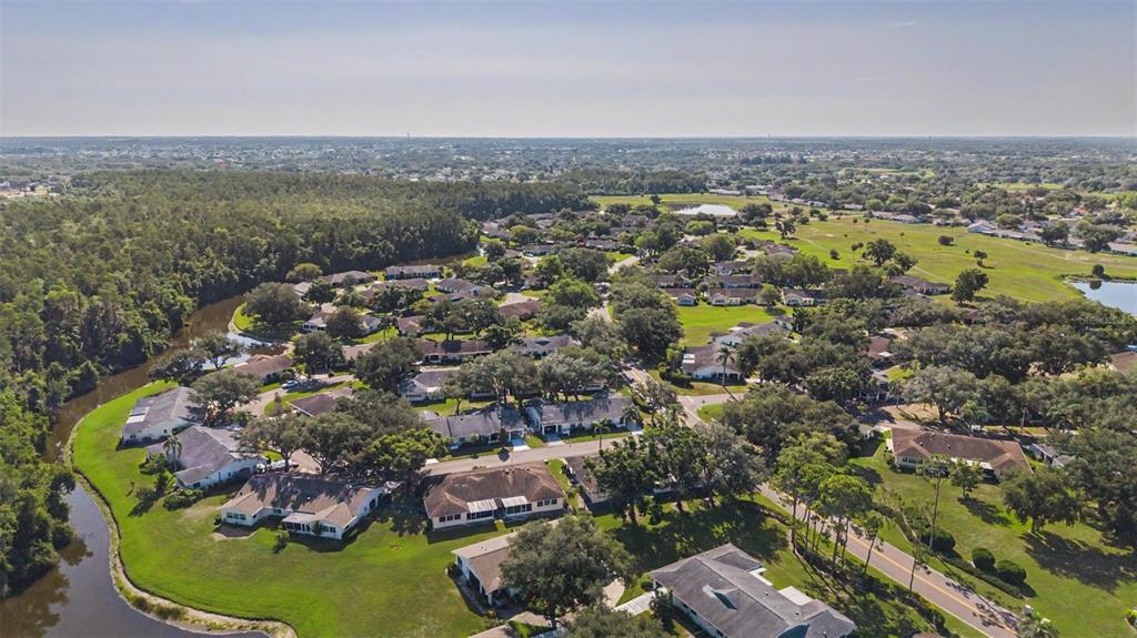 An aerial view shows a residential community with houses, trees, and a winding canal — 1905 HANSON COURT UNIT 305, SUN CITY CENTER, FL