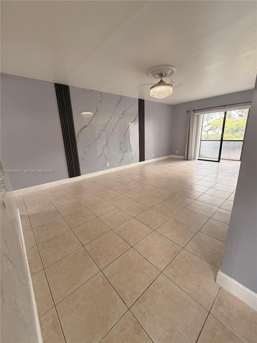 A living room features light tile flooring, a marble-look accent wall, and a crystal chandelier — 266 NW 60th Ave # 266, Margate FL 33063, MARGATE, FL