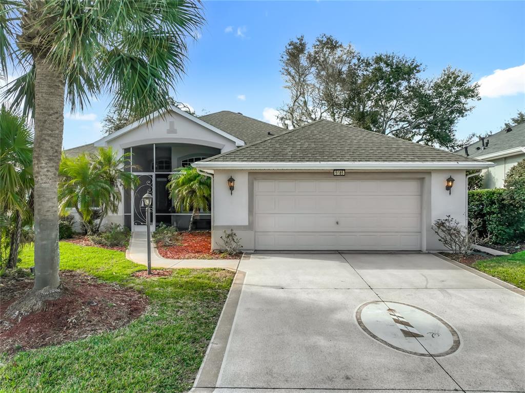 A single-story house with a two-car garage, a screened entryway, and a palm tree — 5685 GULF STREAM STREET, TAVARES, FL