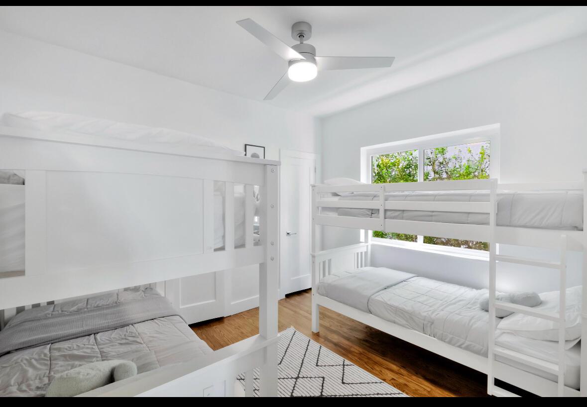 A bedroom features two white bunk beds, hardwood floors, and a ceiling fan — 7825 Byron Avenue, Miami Beach FL 33141, MIAMI BEACH, FL
