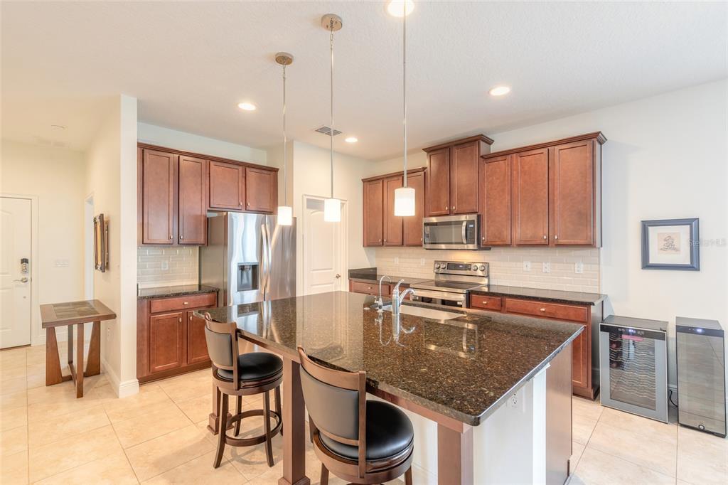 A kitchen with dark wood cabinets, granite countertops, a center island, and stainless steel appliances — 5428 HUTCHINSON STREET, PORT ORANGE, FL