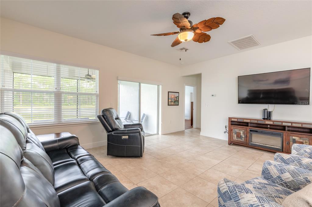 A living room features tile flooring, a ceiling fan, a television, and leather furniture — 5428 HUTCHINSON STREET, PORT ORANGE, FL