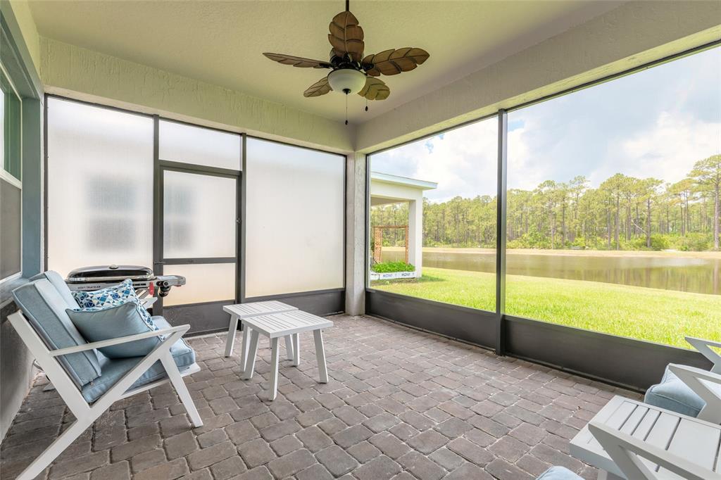 A screened-in patio with paver flooring, outdoor furniture, and a view of a pond — 5428 HUTCHINSON STREET, PORT ORANGE, FL