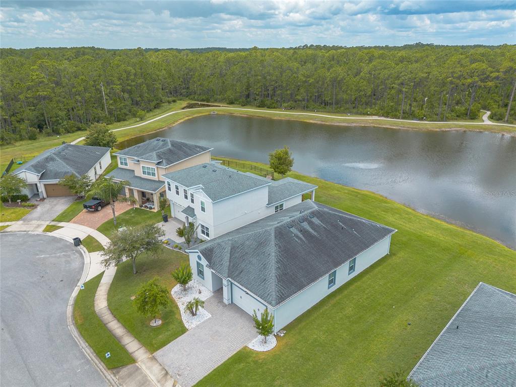 An aerial view shows several suburban houses situated next to a large pond and woods — 5428 HUTCHINSON STREET, PORT ORANGE, FL