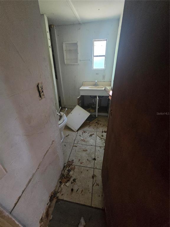 A dilapidated bathroom features a detached cabinet door, a sink, and debris on the floor — 1212 PINE STREET, STARKE, FL