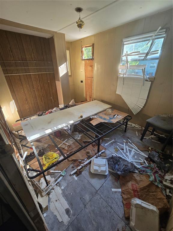 A cluttered, unfinished room with wood-paneled walls, a metal bed frame, and a broken window — 1212 PINE STREET, STARKE, FL