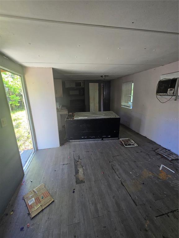 An interior view of a room with gray wood-look flooring, a kitchen island, and debris — 1212 PINE STREET, STARKE, FL