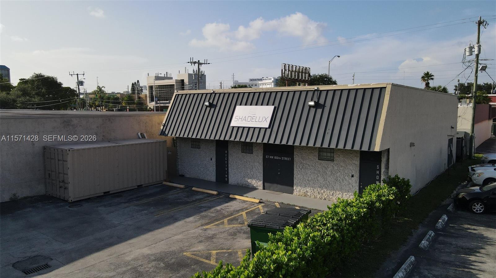 An exterior view of a commercial building with a metal awning and a parking lot — 67 NW 166th St, Miami FL 33169, MIAMI, FL