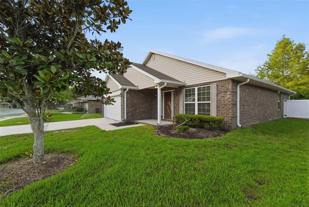 A single-story house with a brick and tan siding exterior, a driveway, and a lawn — 603 CORAL TRACE BOULEVARD, EDGEWATER, FL
