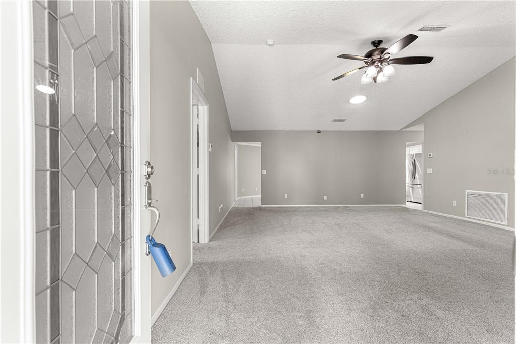 An interior view of a carpeted living room with a vaulted ceiling and ceiling fan — 9878 SW 97TH LANE, OCALA, FL