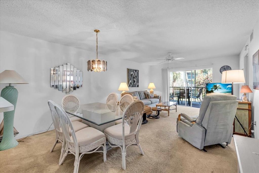 A living and dining area features wicker chairs, a glass table, and a sliding glass door — 6501 STONE RIVER ROAD UNIT 209, BRADENTON, FL