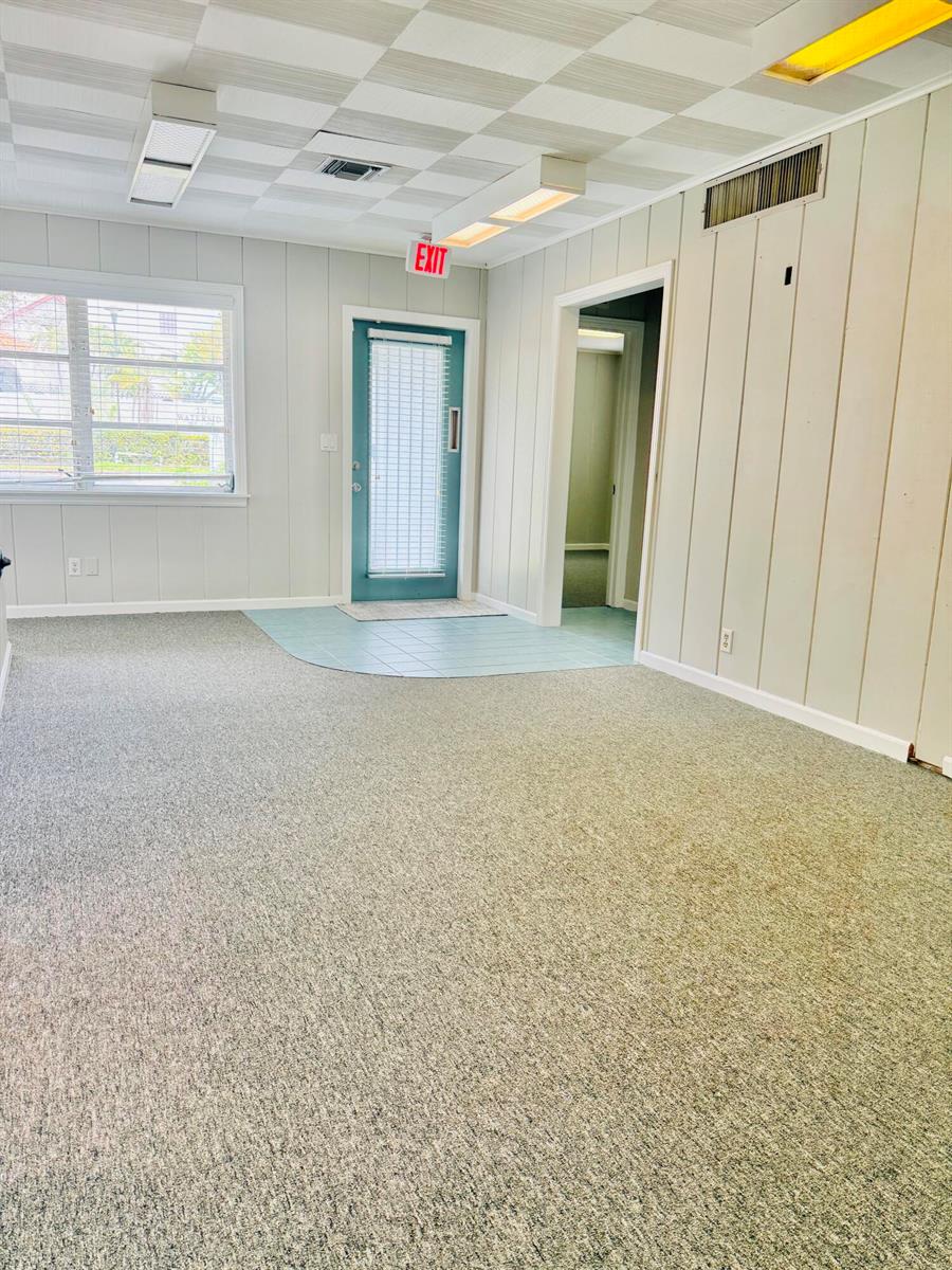 An interior room features gray carpeting, light-colored wood paneling, a teal door, and a tiled entryway — 218 SE Osceola Street, Stuart FL 34994, STUART, FL