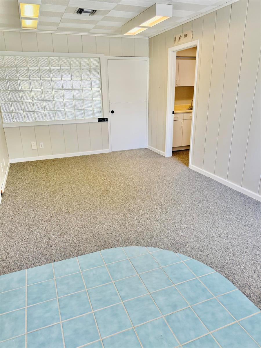 An interior room features gray carpet, light-colored paneling, a glass block wall, and tile flooring — 218 SE Osceola Street, Stuart FL 34994, STUART, FL