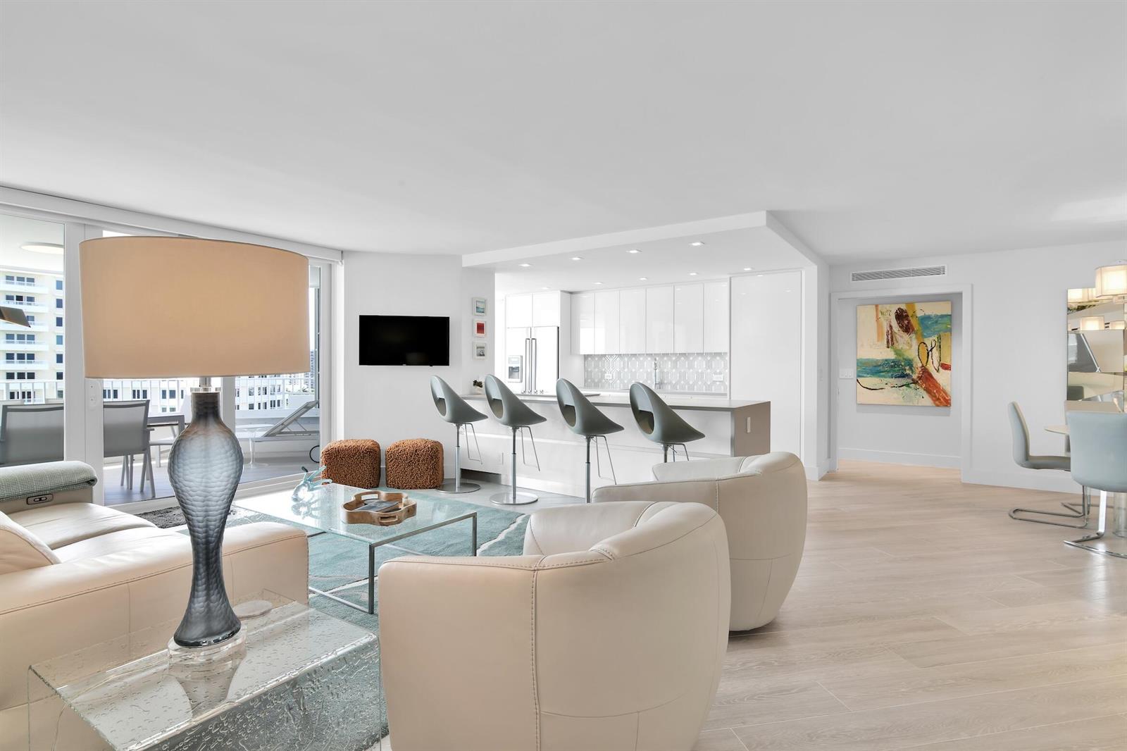 A bright, modern living room and kitchen area with white cabinetry and light wood flooring — 550 S Ocean Boulevard # 1004, Boca Raton FL 33432, BOCA RATON, FL