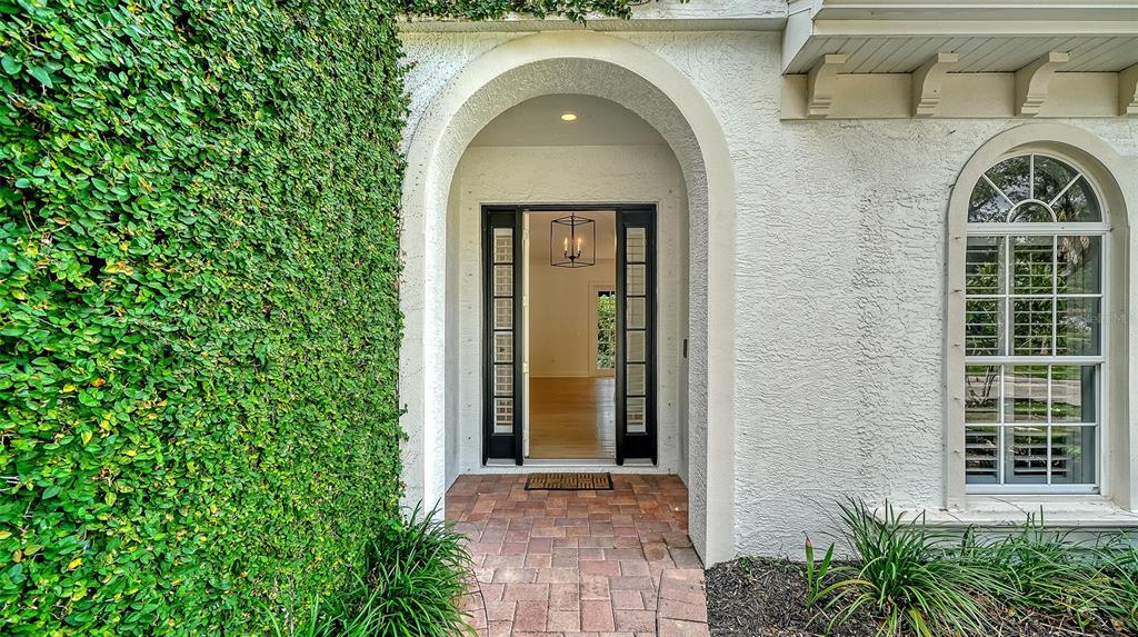 An arched entryway with a brick floor leads to a front door with glass panels — 1704 FORTUNA STREET, SARASOTA, FL