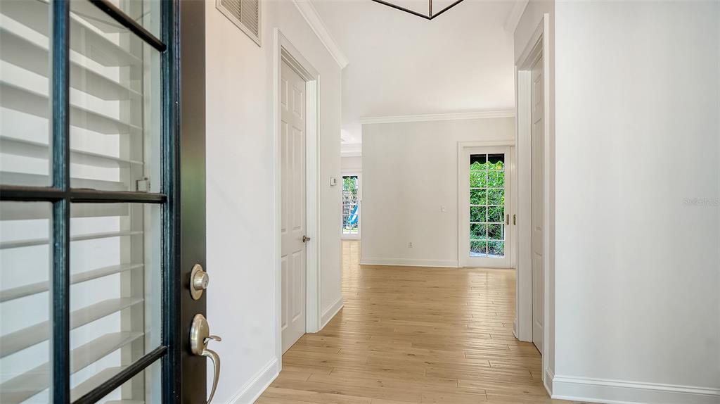 A bright entryway features light wood-look flooring, white walls, and a glass-paned exterior door — 1704 FORTUNA STREET, SARASOTA, FL