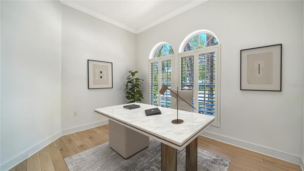 A home office features a marble-topped desk, arched windows with shutters, and light wood flooring — 1704 FORTUNA STREET, SARASOTA, FL