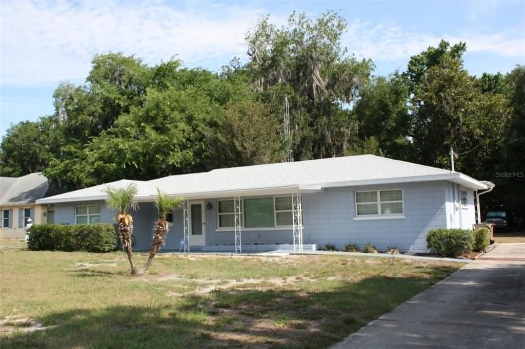 A light blue, single-story concrete block house with a white roof and metal porch supports — 4331 MAGNOLIA AVENUE, LEESBURG, FL