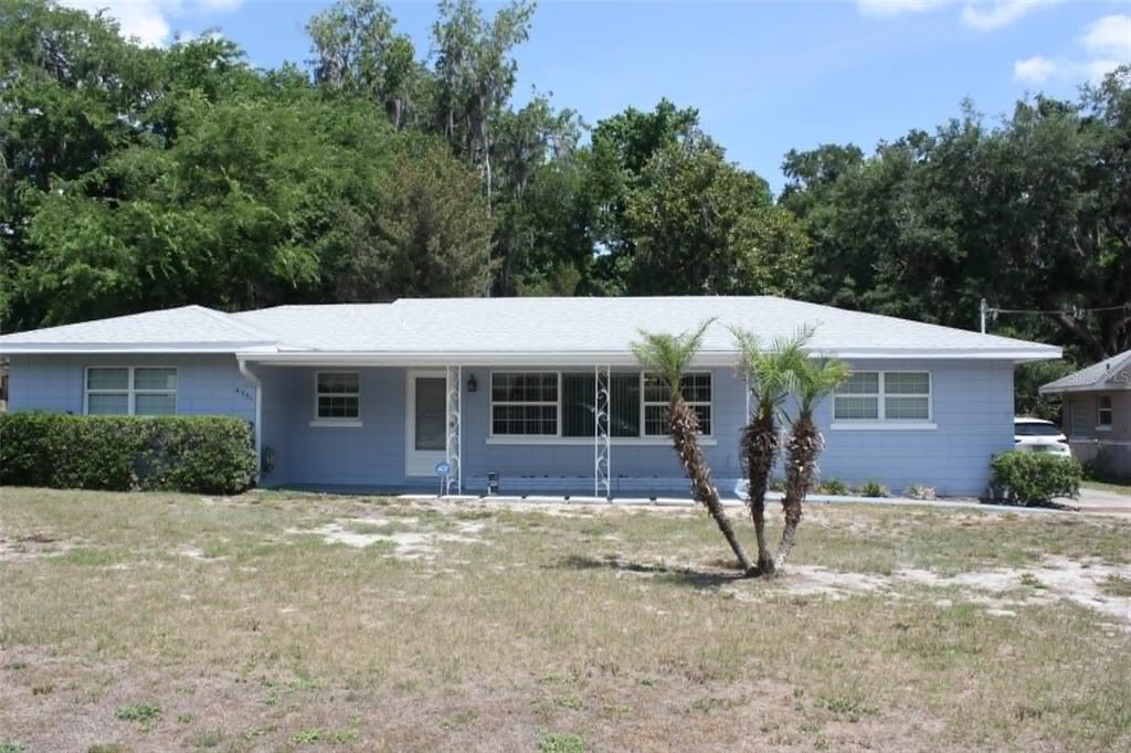 A single-story light blue house with a white roof and a front porch with metal columns — 4331 MAGNOLIA AVENUE, LEESBURG, FL