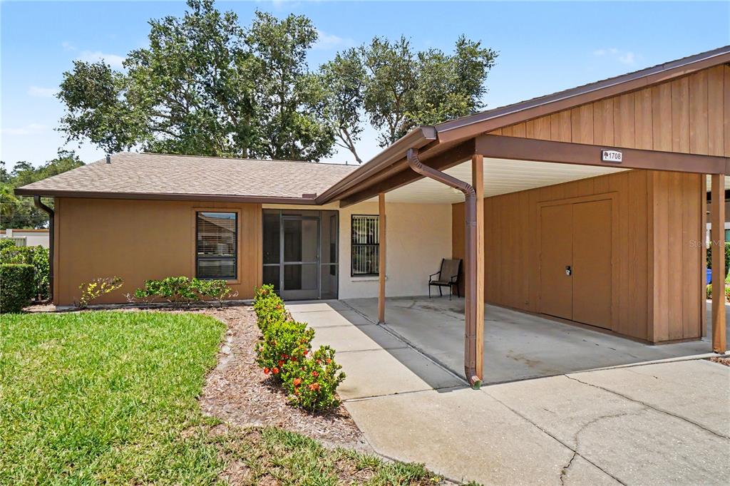 A single-story house exterior features a brown facade, a concrete driveway, and a covered carport — 1708 CURRY TRAIL UNIT 3, NOKOMIS, FL