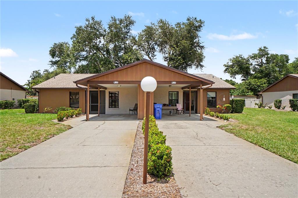 A single-story duplex with a shared driveway, covered carports, and a central landscaping strip — 1708 CURRY TRAIL UNIT 3, NOKOMIS, FL