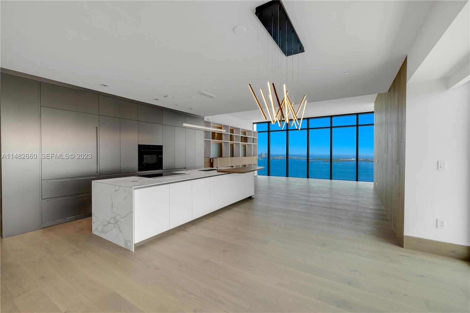 A modern kitchen features a marble island, metallic cabinetry, and floor-to-ceiling windows overlooking the ocean — 1451 Brickell Ave # 4403, Miami FL 33131, MIAMI, FL