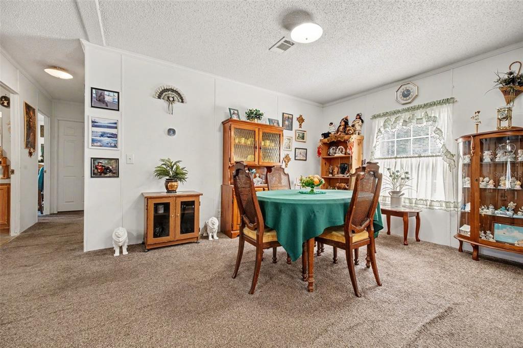A dining room features a round table with a green cloth, wood furniture, and carpet — 2205 HIBISCUS AVENUE, MIDDLEBURG, FL