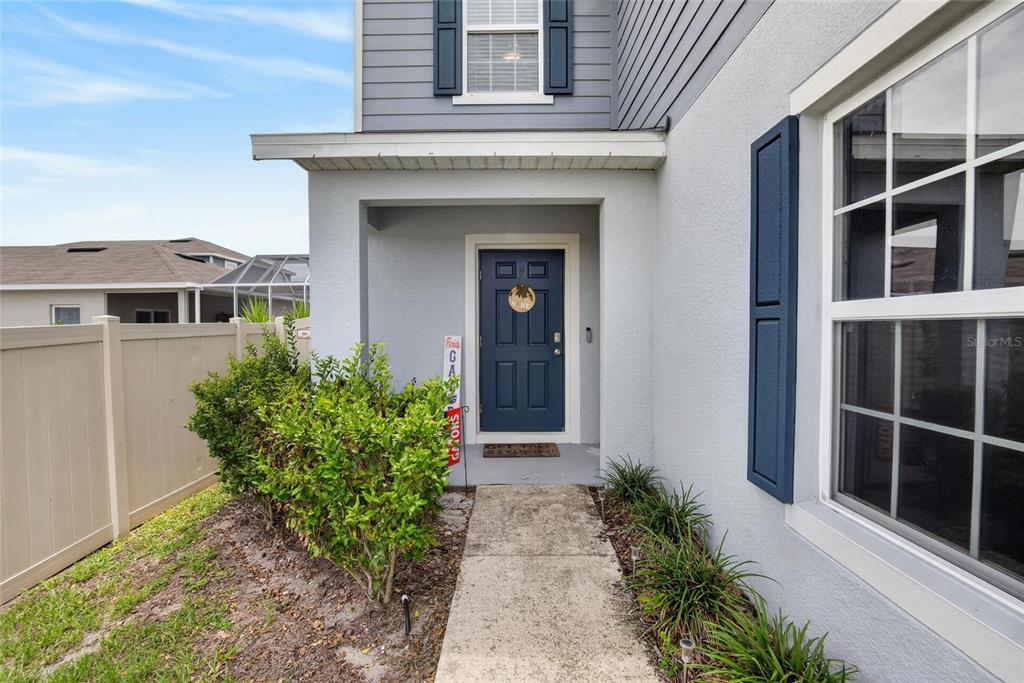 A concrete walkway leads to the blue front door of a two-story suburban home — 3706 ZEPHYR PRESERVE PLACE, ZEPHYRHILLS, FL