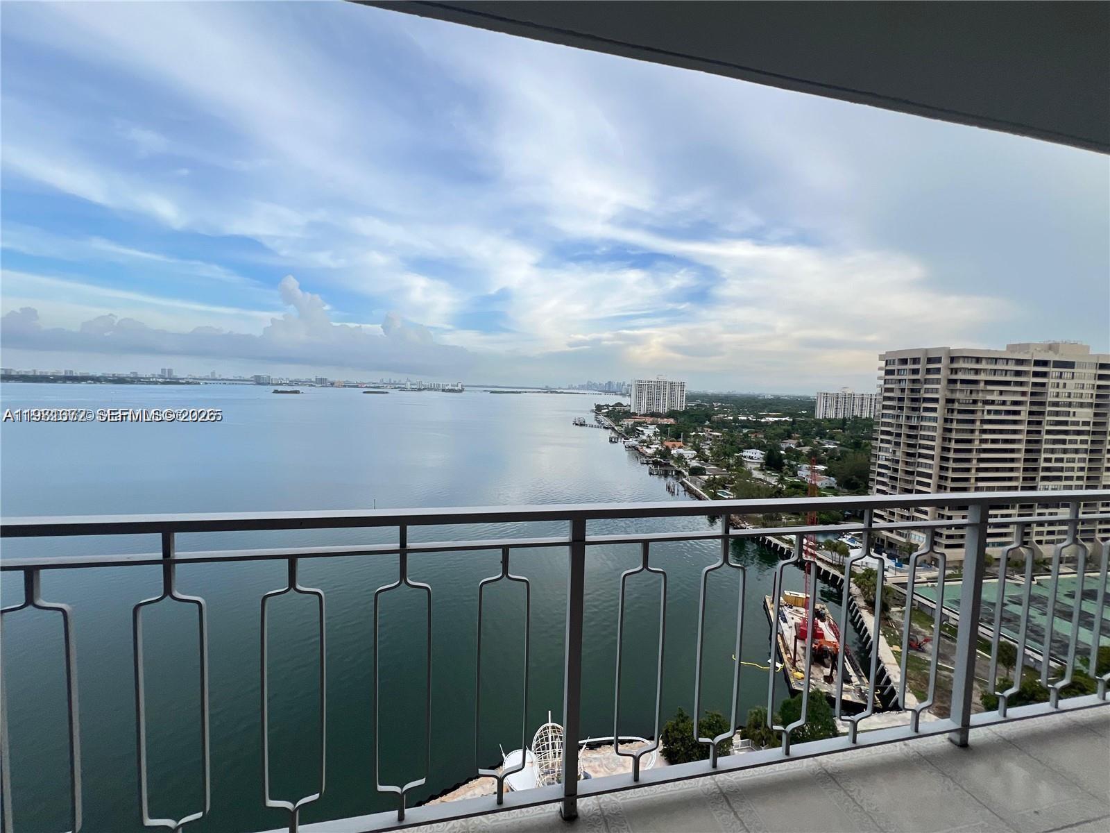 A balcony view overlooks a large body of water, coastal buildings, and a construction barge — 11111 Biscayne Blvd # 20E, Miami FL 33181, MIAMI, FL