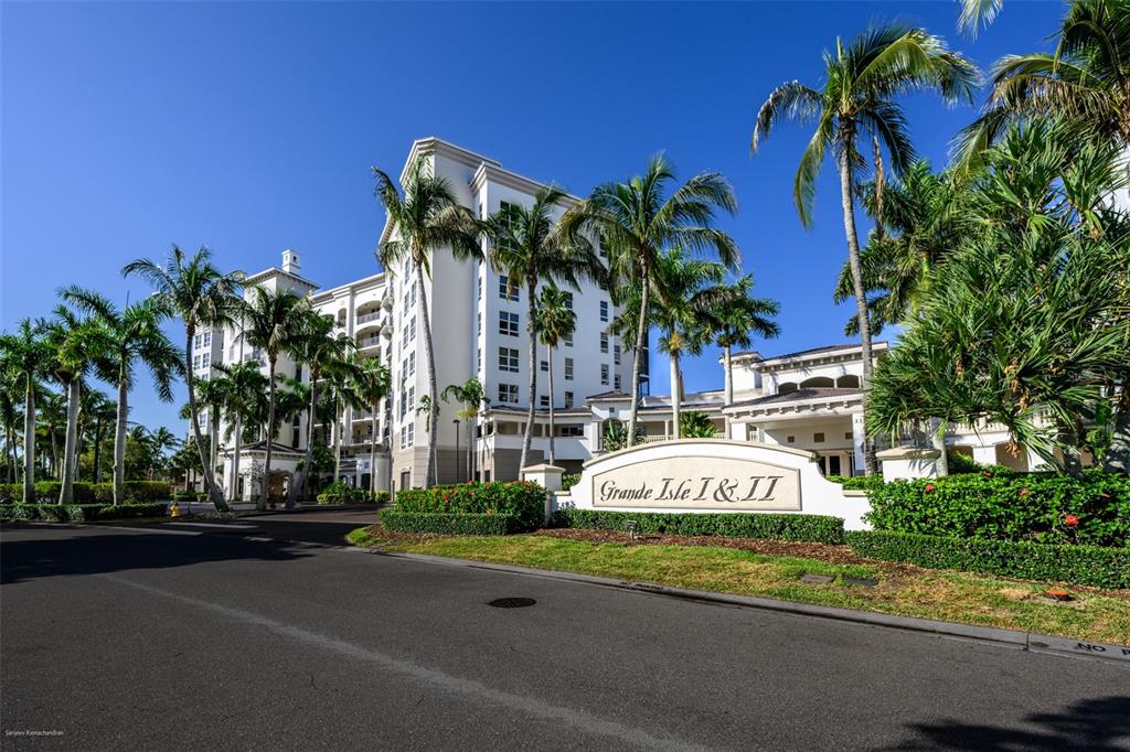 A multi-story white residential building with palm trees and a sign reading Grande Isle I & II — 3313 SUNSET KEY CIRCLE UNIT 306, PUNTA GORDA, FL