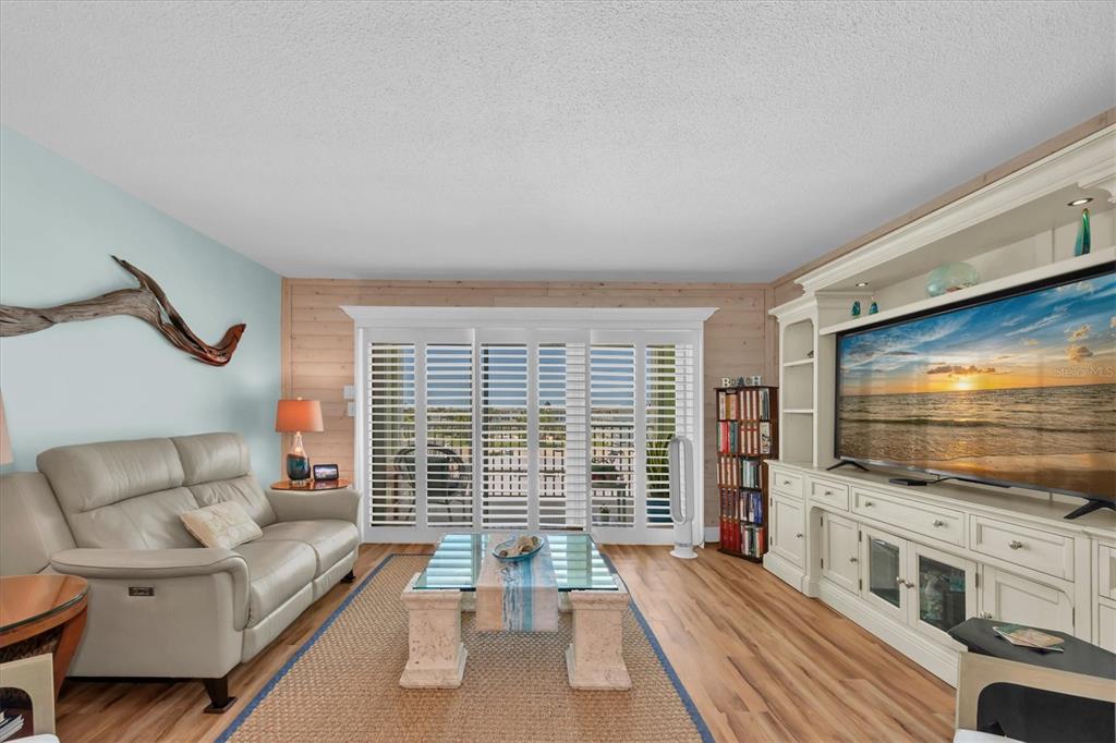 A living room features a light-colored sofa, a glass coffee table, and a large entertainment center — 420 64TH AVENUE UNIT 402E, ST PETE BEACH, FL