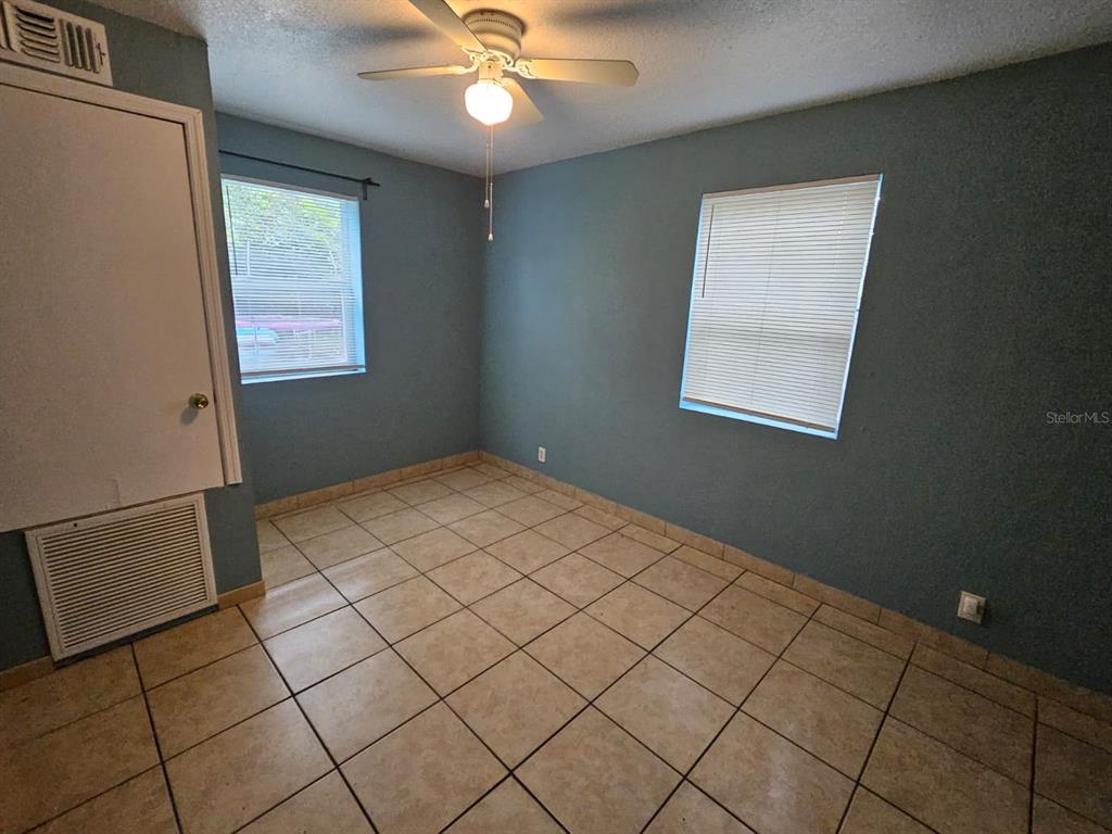 A bedroom with blue walls, tiled flooring, a ceiling fan, and two windows with blinds — 118 N VAN BUREN AVENUE, ORLANDO, FL