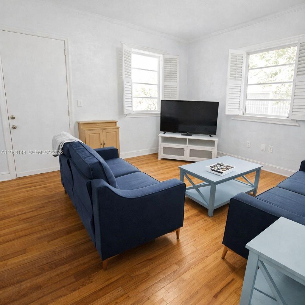 A living room features two blue sofas, a television on a stand, and hardwood floors — 928 Euclid Ave # 6, Miami Beach FL 33139, MIAMI BEACH, FL