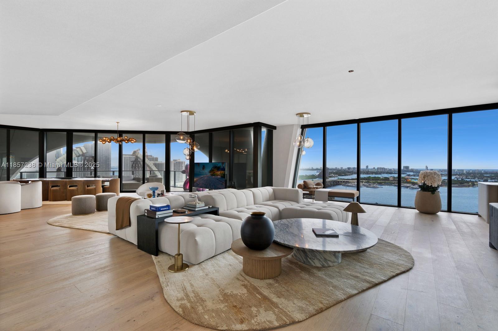 A spacious living room features a large sectional sofa, marble coffee table, and floor-to-ceiling windows — 1000 Biscayne Blvd # 2402, Miami FL 33132, MIAMI, FL