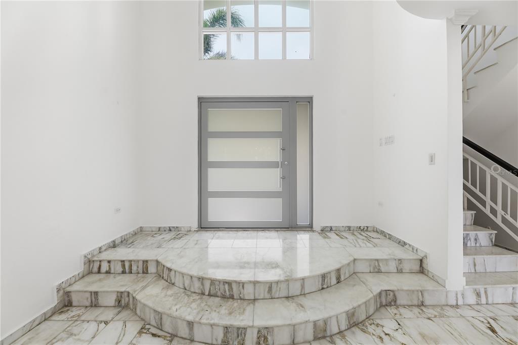 A foyer features a marble-tiled raised platform, a modern gray door, and a staircase — 97 CALLE PITIRRE MONTEHIEDRAS, SAN JUAN, PR