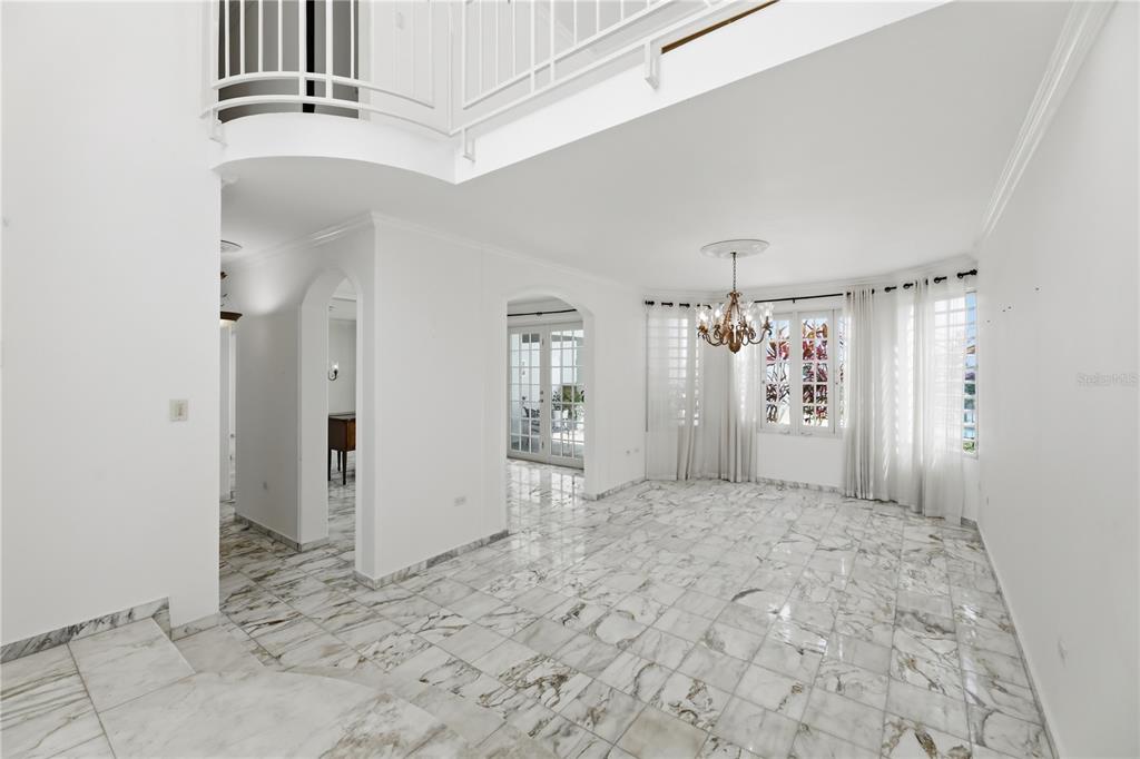 A bright, high-ceilinged room features white marble flooring, a chandelier, and arched doorways — 97 CALLE PITIRRE MONTEHIEDRAS, SAN JUAN, PR