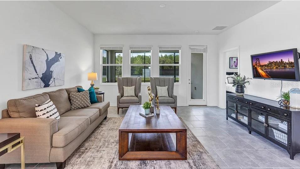 A living room features a beige sofa, two gray armchairs, a wooden coffee table, and television — 639 TERRAPIN DRIVE, DEBARY, FL