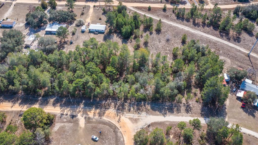 An aerial view shows a wooded lot with several houses and dirt roads — 5851 HILLRIDGE ROAD, KEYSTONE HEIGHTS, FL