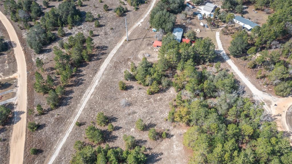 An aerial view shows a rural lot with dirt roads, scattered trees, and several buildings — 5851 HILLRIDGE ROAD, KEYSTONE HEIGHTS, FL