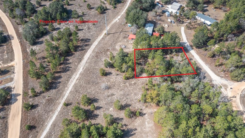 An aerial view shows a rectangular plot of land outlined in red amidst wooded terrain — 5851 HILLRIDGE ROAD, KEYSTONE HEIGHTS, FL
